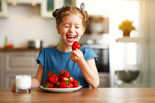 girl has strawberries and milk for a snack
