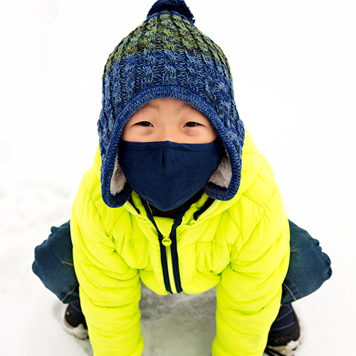 Little kid outside in the snow with a mask