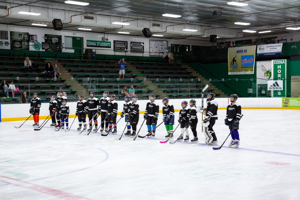A line of boys in skates standing in a hockey rink