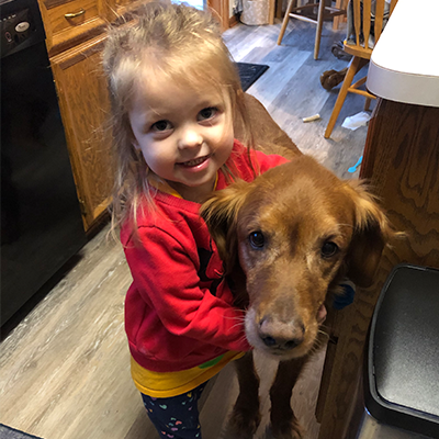 Margaret smiling holding on to her dog