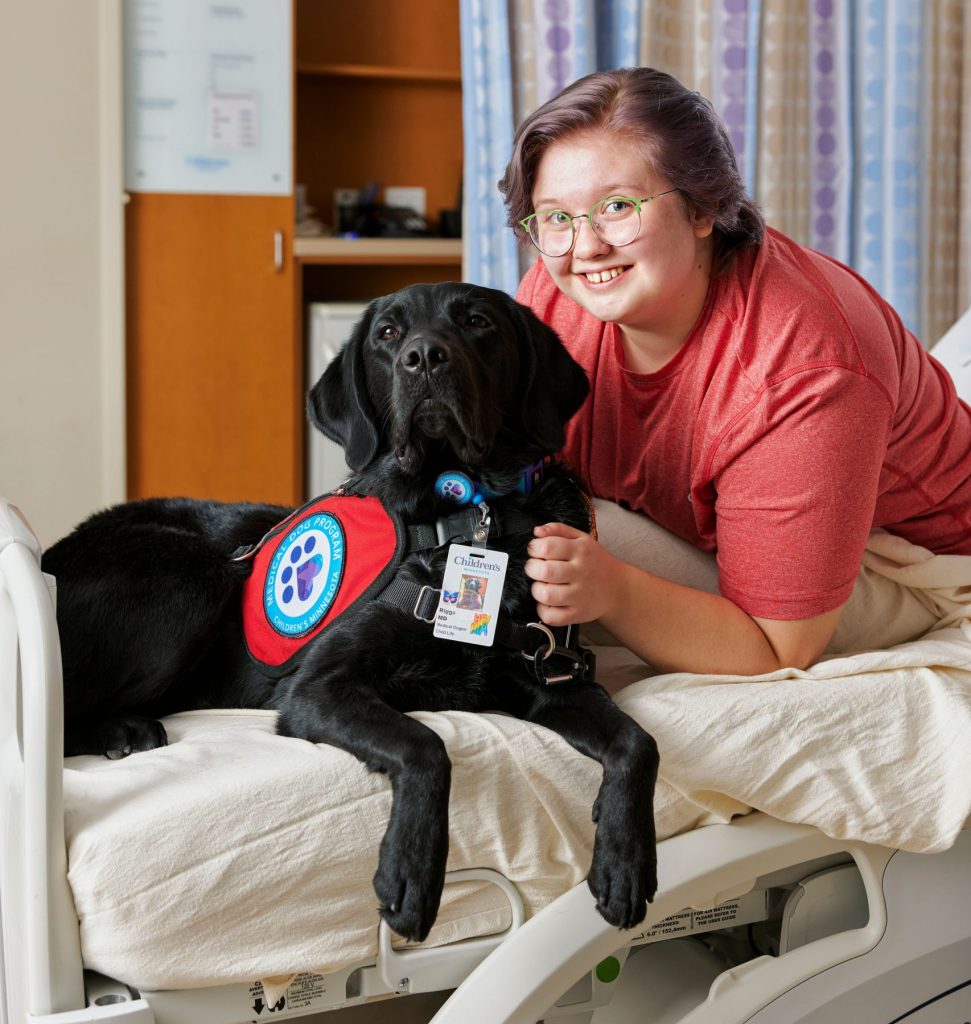 A young person with Riggs, the Children's Minnesota medical dog.