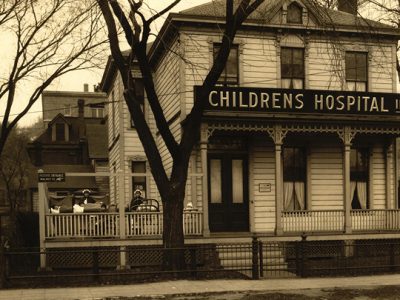 an early 1900s house with a sign above the front door that says, "Children's Hospital Inc."