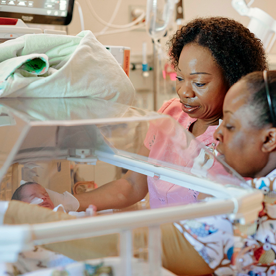 a present day photo of two providers standing over a newborn.