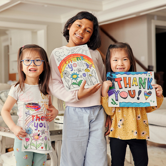 Three sisters hold up signs that say "Thank you!"