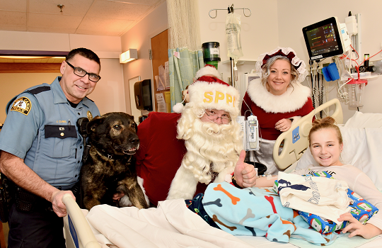 A St. Paul Police officer with Santa with a patient in the hospital