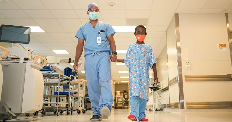 Surgeon leading child down hallway