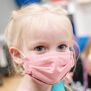 a girl wearing a mask looks at the camera