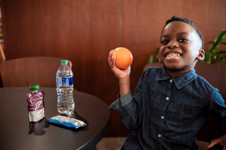 Little boy holding an orange in his right hand