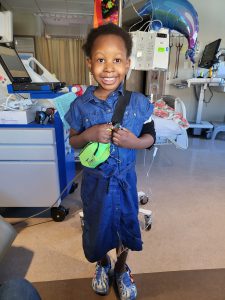 Photo of Temi smiling, wearing a demin dress in her hospital room