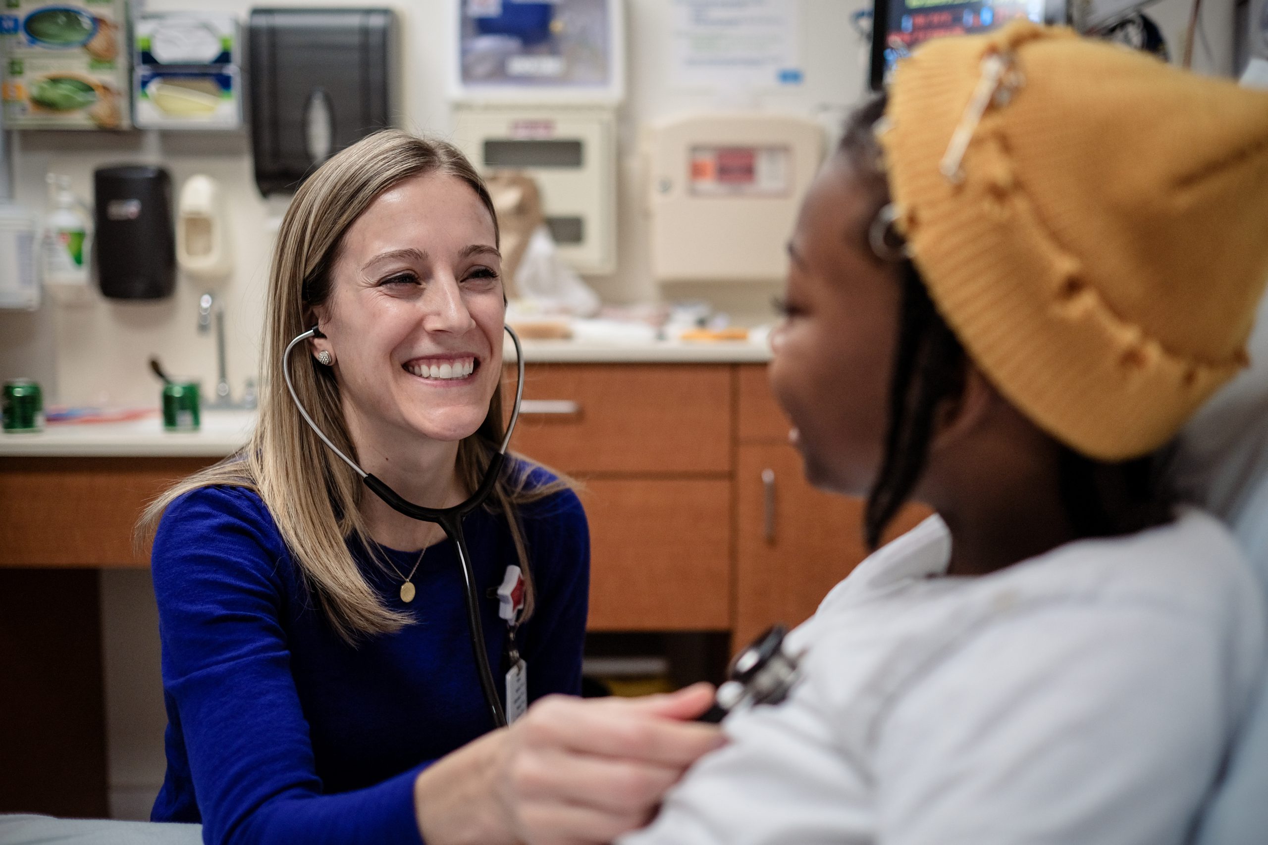 Smiling female doctor listens to heartbeat of young patient