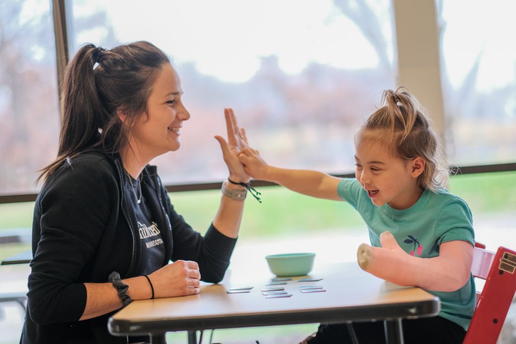 Chloe and her therapist, Erin Diedrich, OTR/L, high-fiving