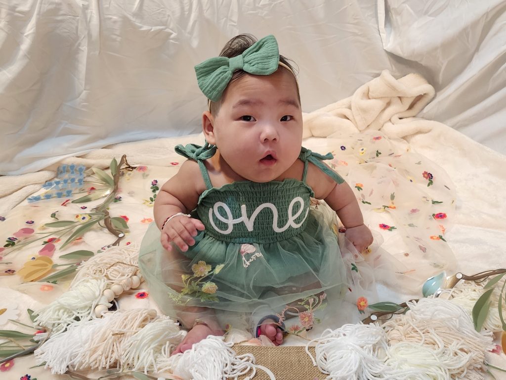 Gracelyn sitting up for in a 'one' dress for her first birthday