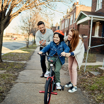 parents teaching son how to ride a bike