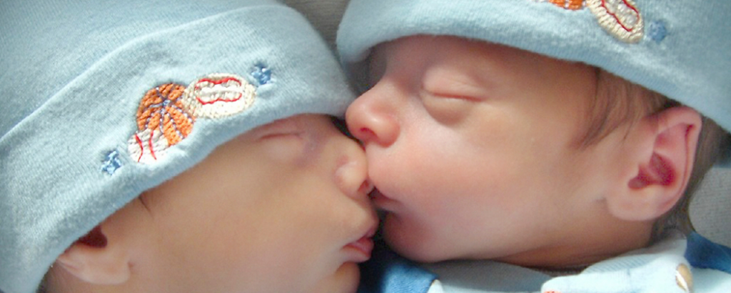 Two newborn twins sleeping next to each other.
