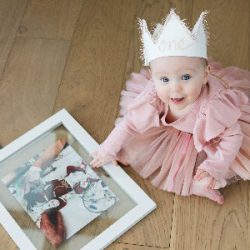 Whitney, on her first birthday, wears a pink dress and a white crown.