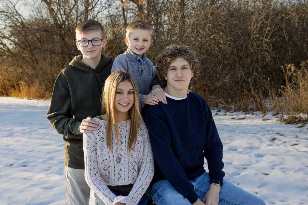 Four children smiling for a photo outside in the snow.