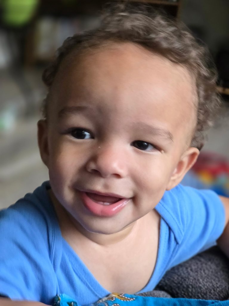 A'zarion smiles as he holds to stand. He wears a blue shirt