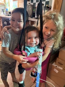Archer in a swing being hugged by his brother Connor and sister Melody.