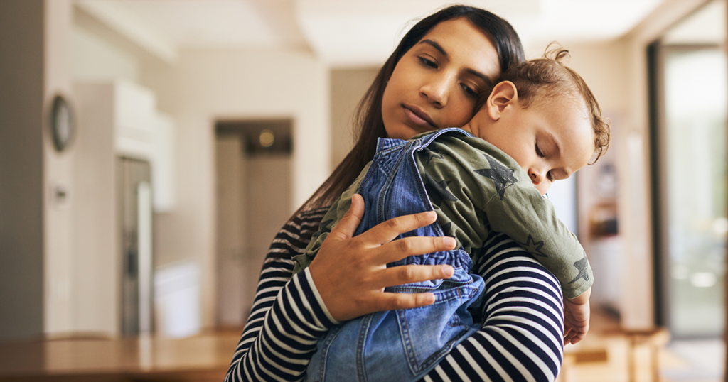 Sad child being held by mom.