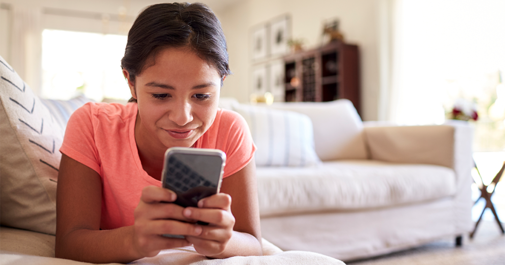 Teenage girl in a pink shirt using her cellphone