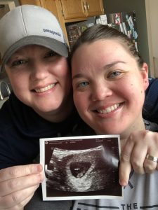 Katie and Betsy holding a photo of their ultrasound.