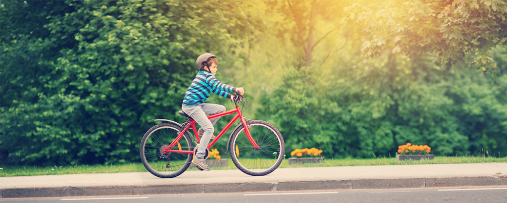 Adolescent boy riding a bike on the sidewalk