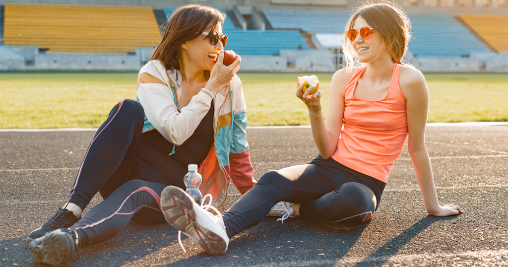 Mother and teenage daughter eating apples after going for a walk