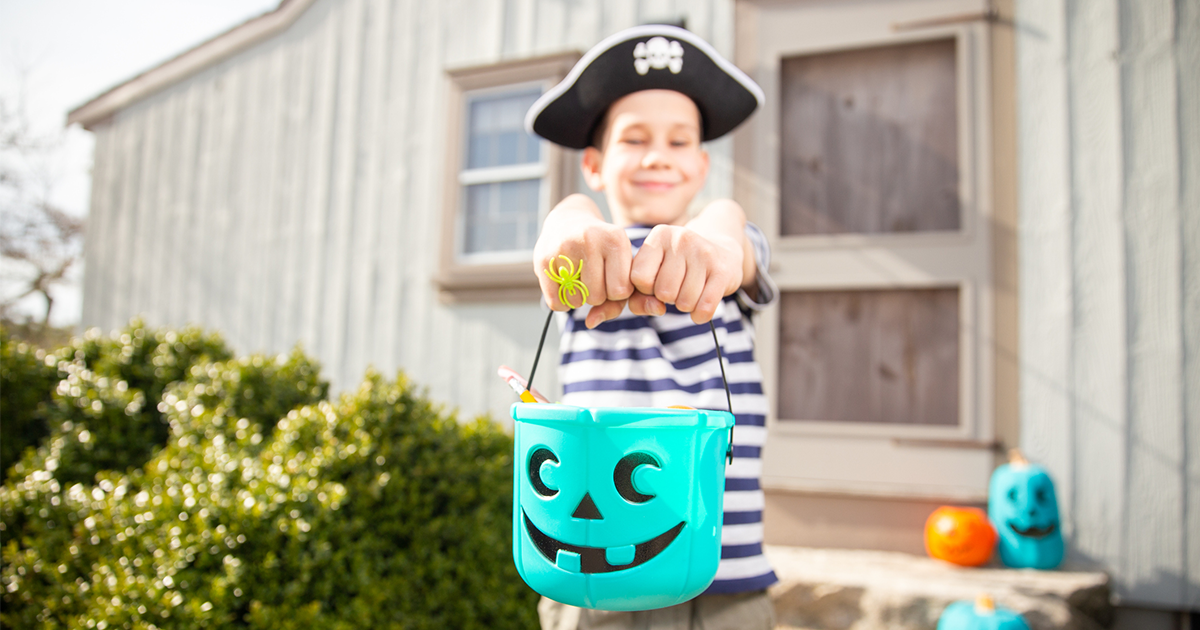 Boy dressed as pirate holding a teal pumpkin