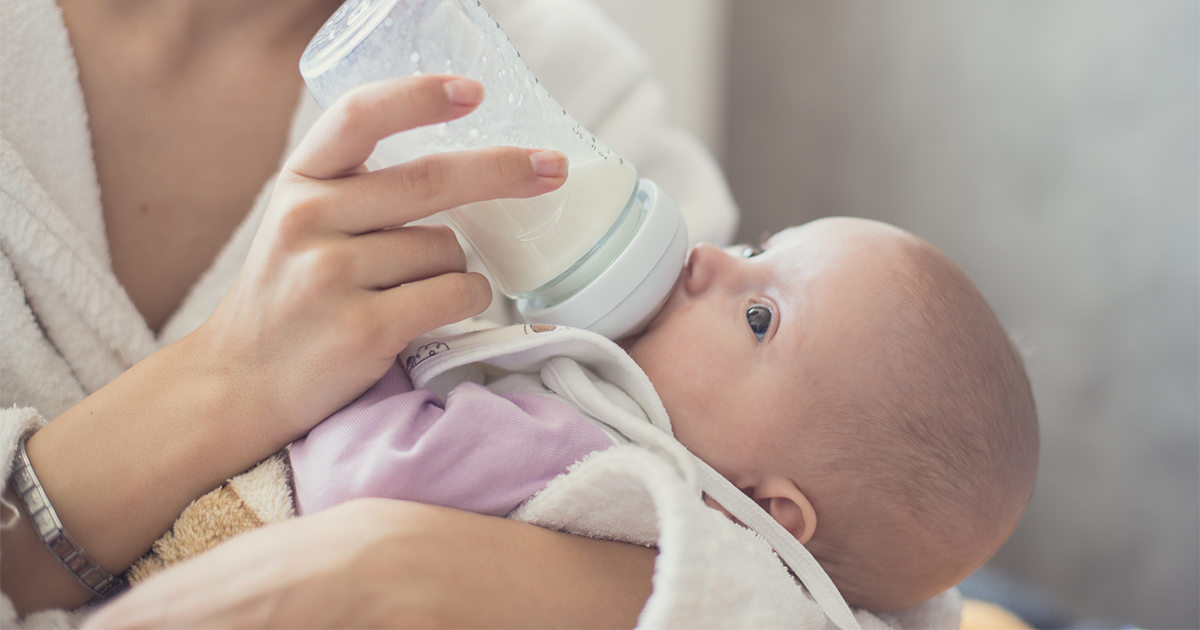 Mom feeding her baby pumped breastmilk with a bottle