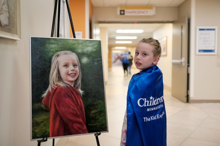 Brielle standing next to her Beyond the Diagnosis portrait.