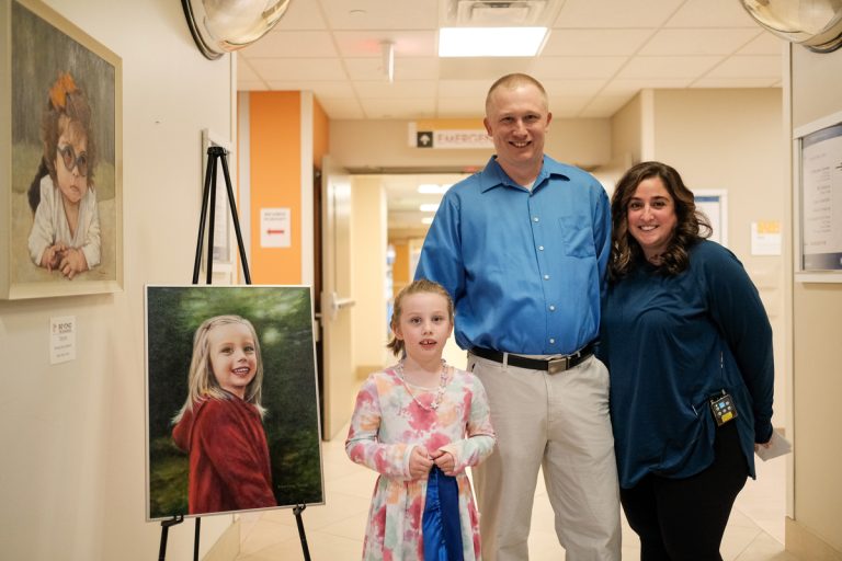 Brielle and her parents next to Brielle's portrait