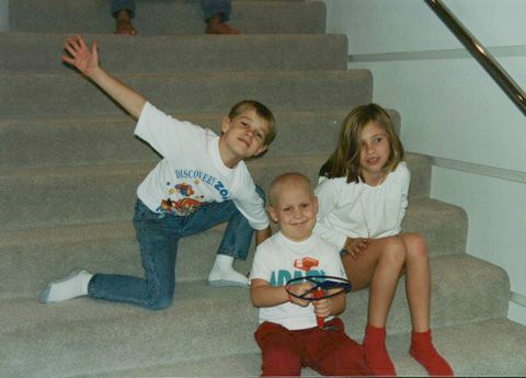 Ashley and her two siblings sitting on the stairs at home