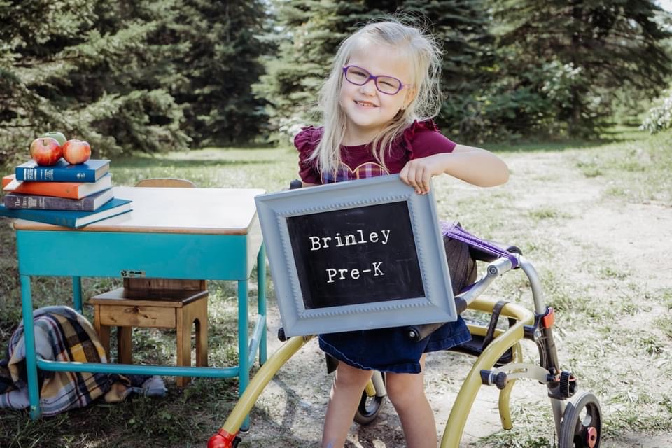 Brinley holding up a sign that says Brinley Pre-K