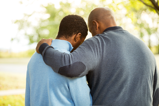 father with arm around son