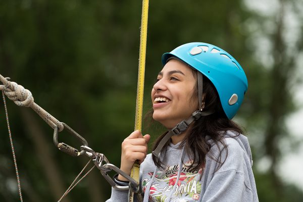 A camper wearing her helmet, prepares for the ropes course