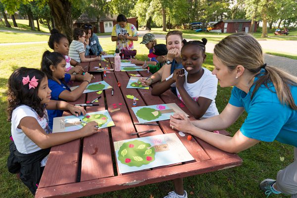 Campers sit at a picnic table creating artwork