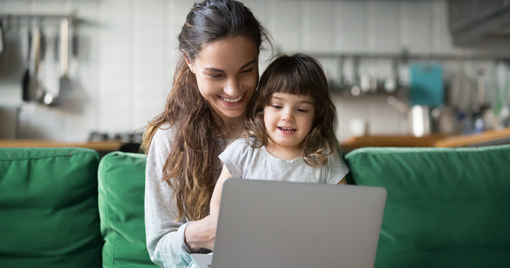 Mom on computer with daughter at home.