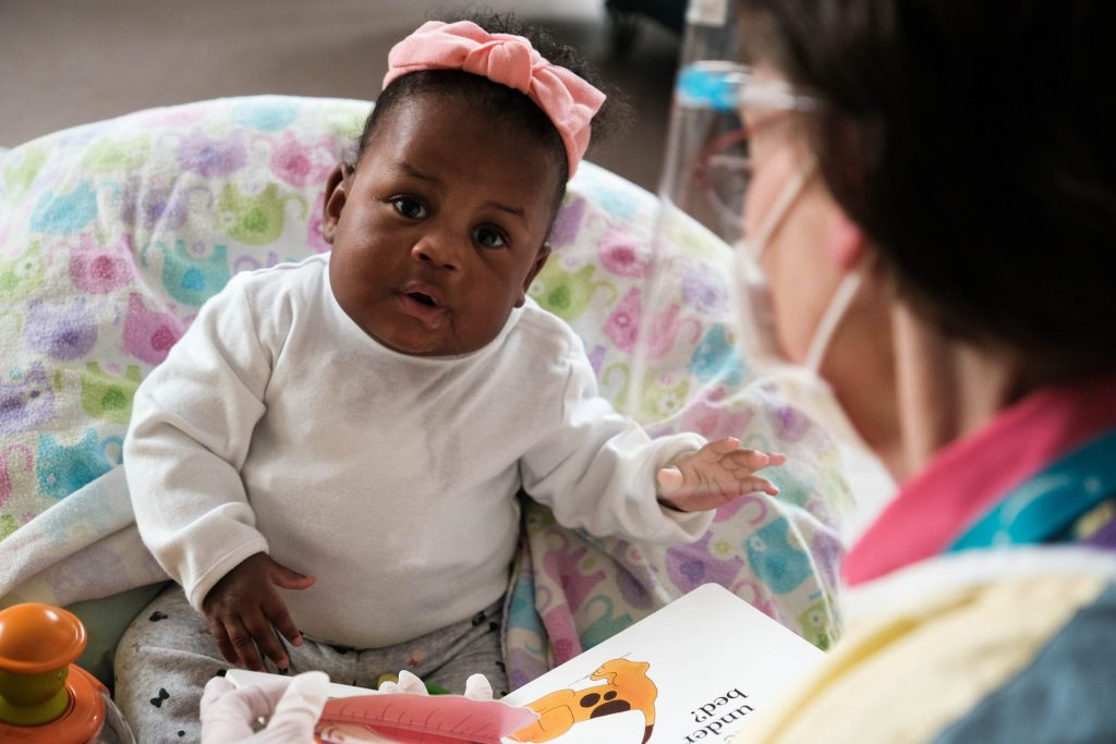 A child life specialist reading to a young baby