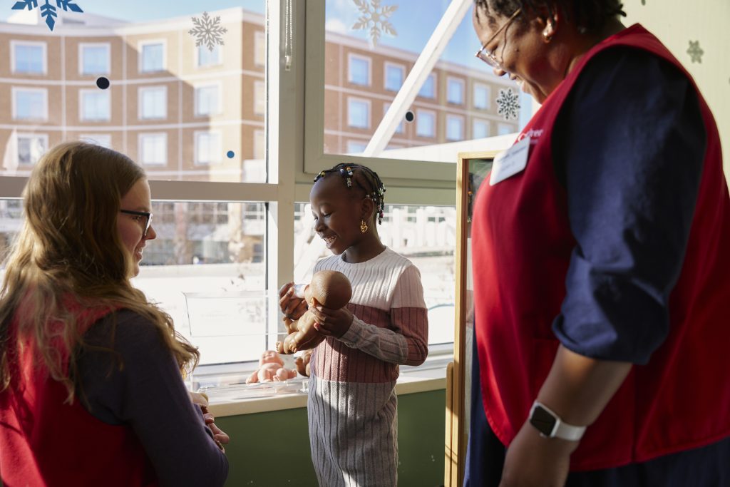 Temi with volunteers playing with a doll