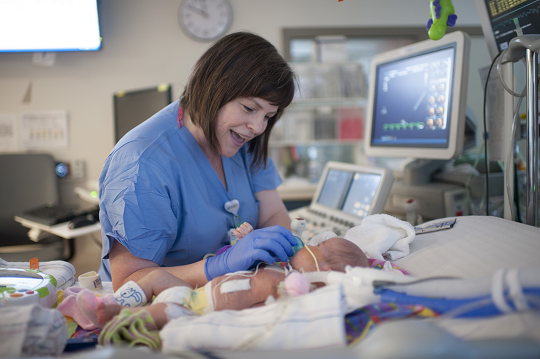 Children's Minnesota nurse, checking in on a baby in the ICU