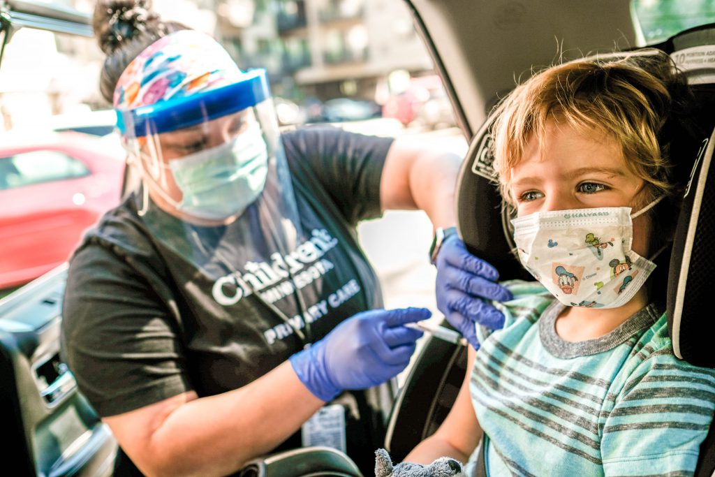 Child receives immunization in car through drive up care