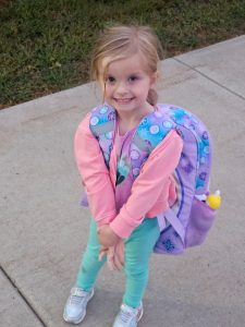 Evelyn smiling and wearing a backpack.