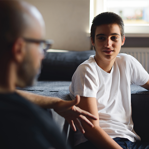 Father talking with son on the couch at home