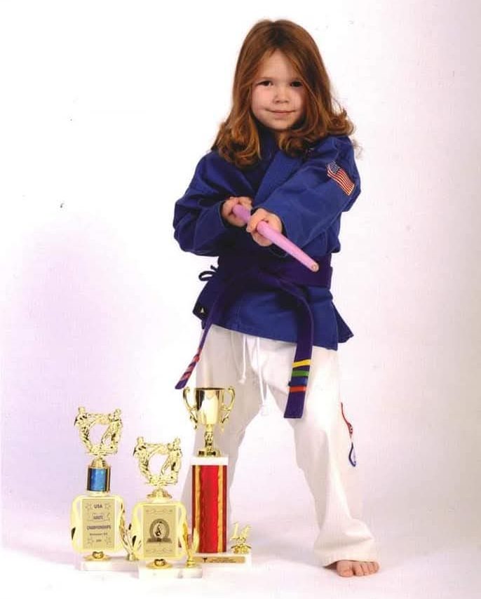 Young Jentai poses for karate photos with throphies.