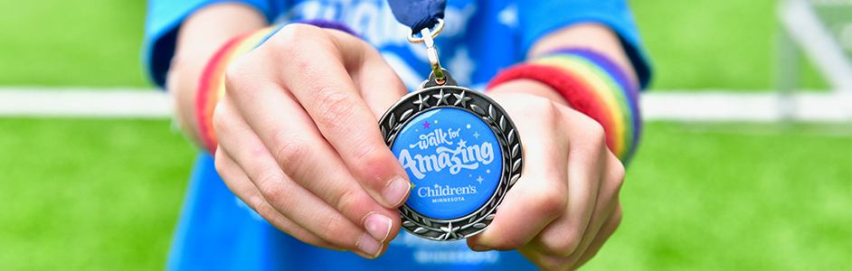 A kid holding up a Walk for Amazing medal