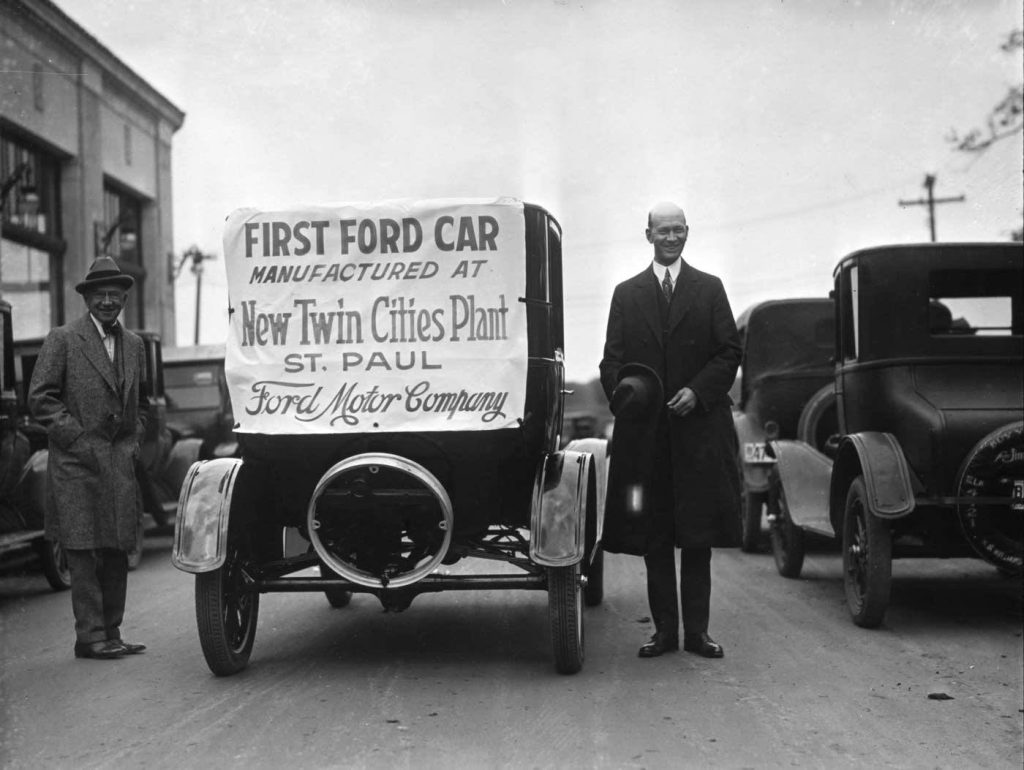 Ford Motor Company Founder Henry Ford standing next to a car