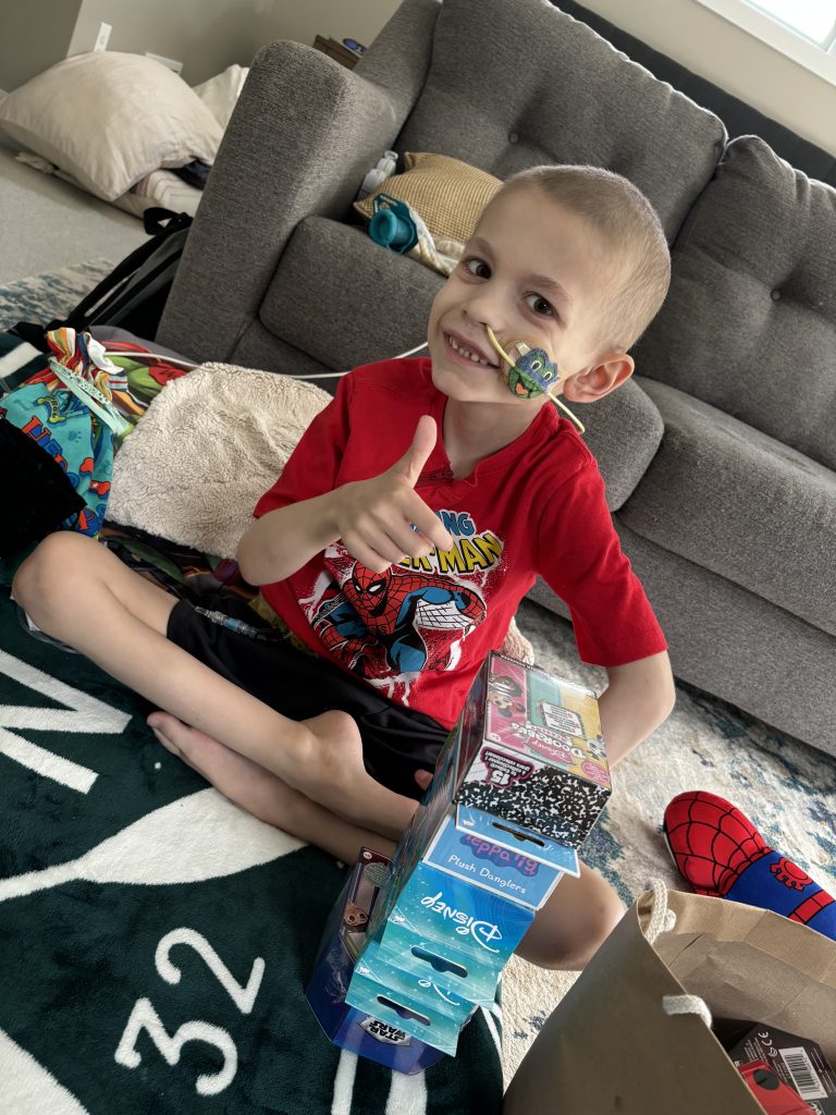 Freddie with toys and giving a thumbs up.