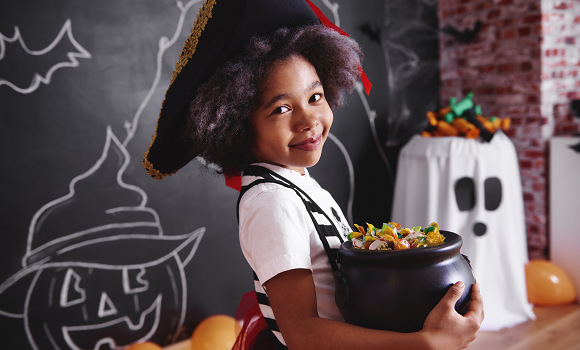 Girl wearing pirate costume holding a bowl of candy