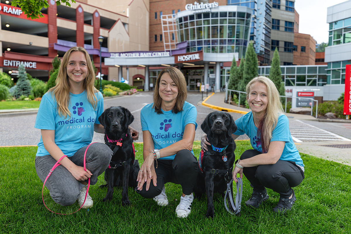 3 people and 2 black lab dogs