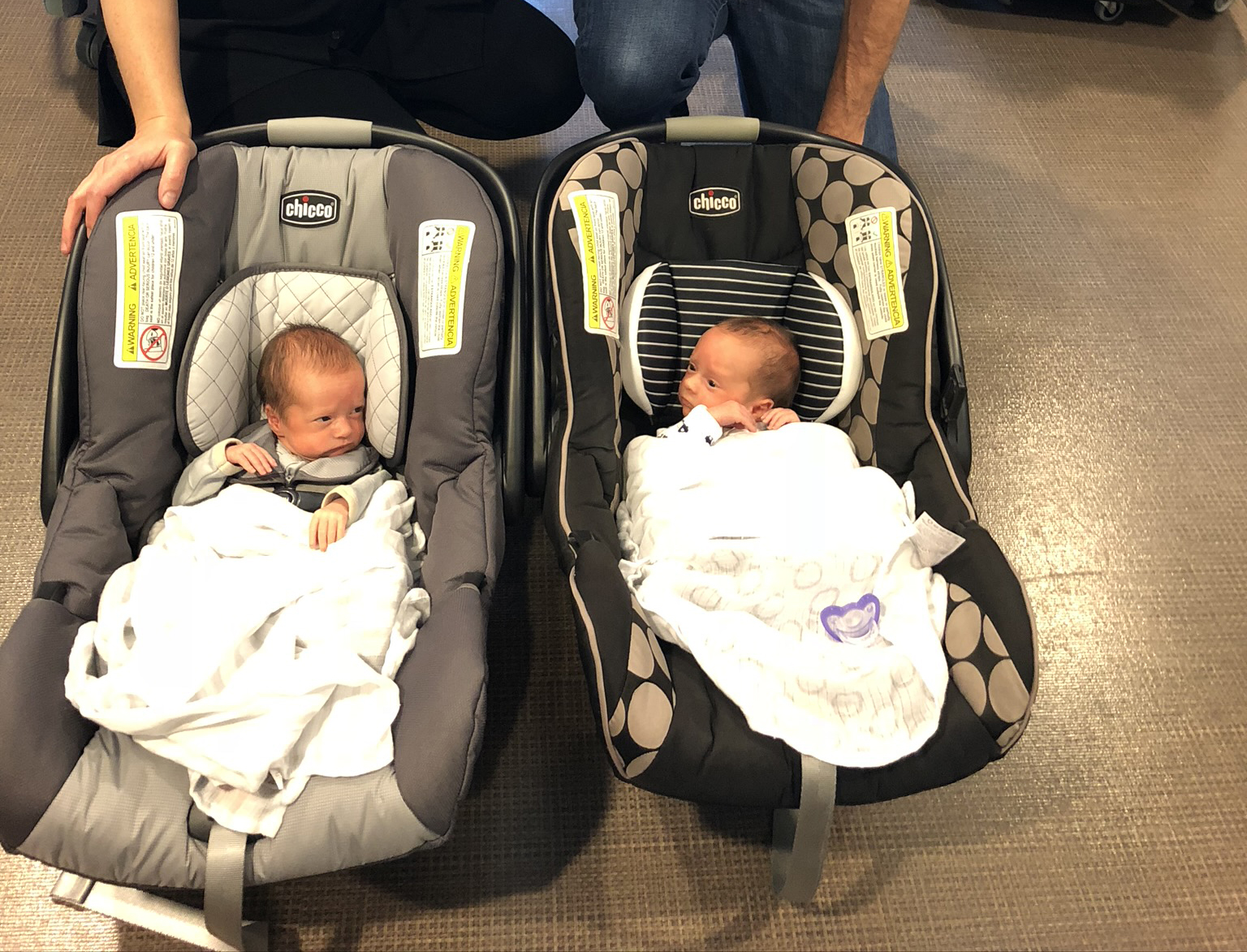 Twins heading home from the NICU in car seats.